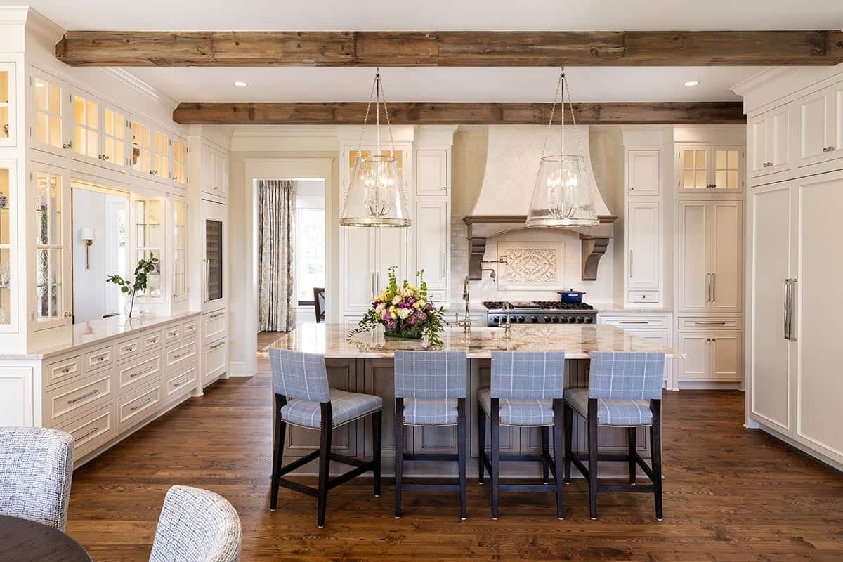 Kitchen with white cabinetry, glass pendant lights, and reclaimed wood beam