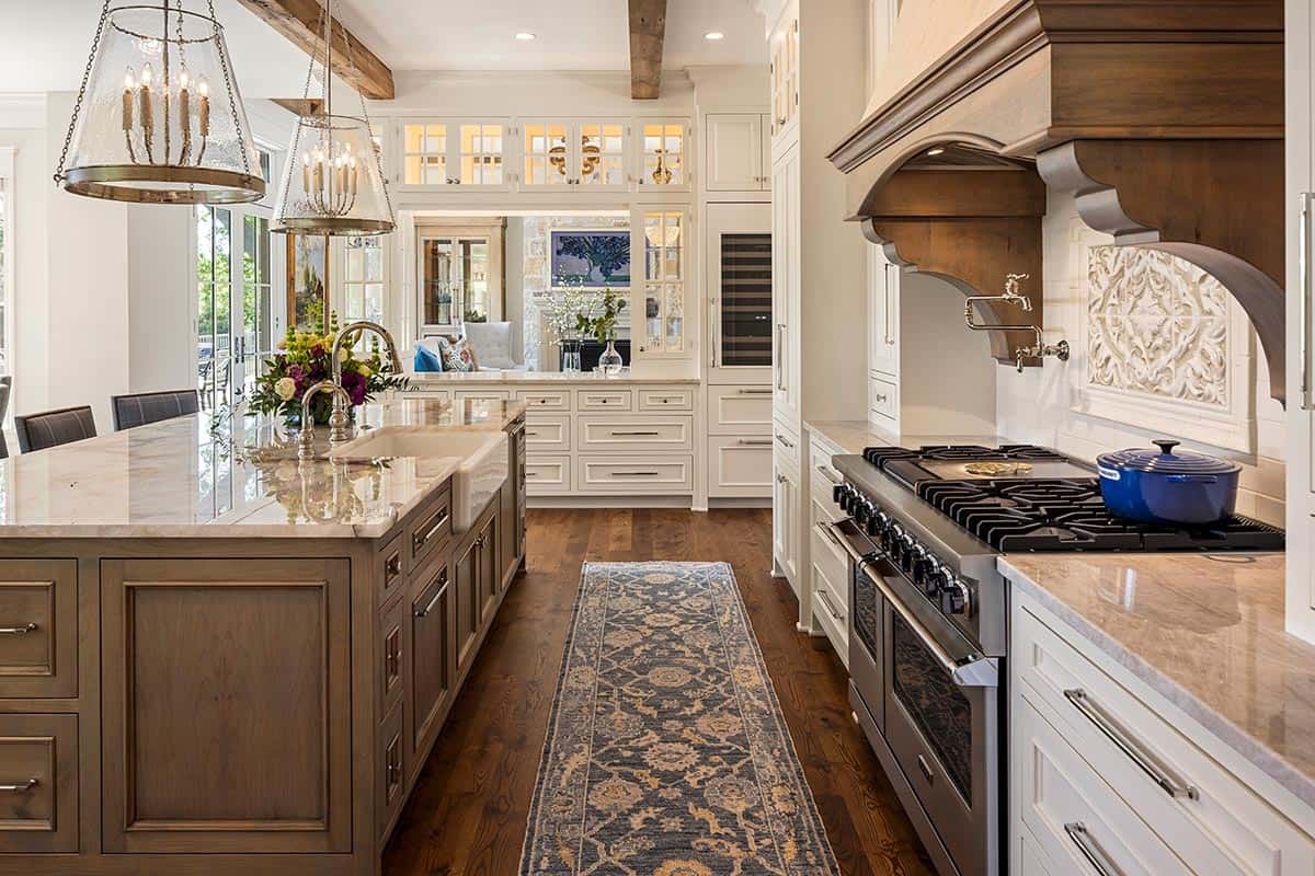 Kitchen view toward carved wood range hood and gas cooktop