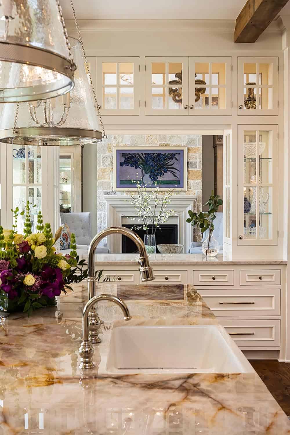 Kitchen sink area with marble countertop and view into stone fireplace living room