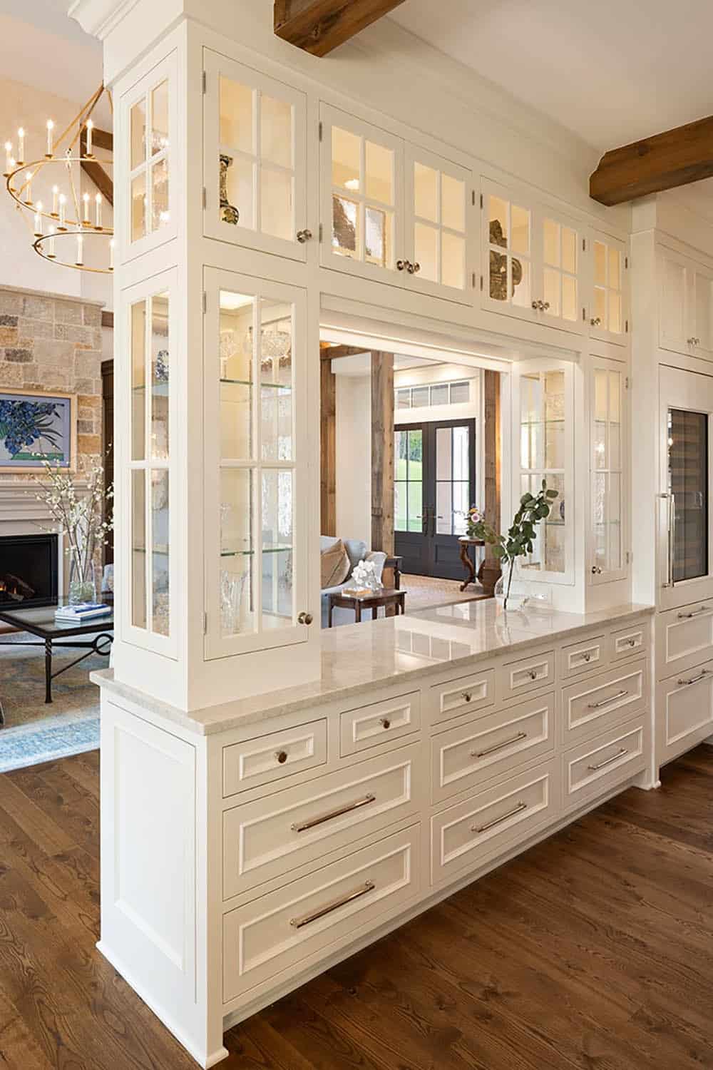 Glass display cabinetry framing pass-through view into living room