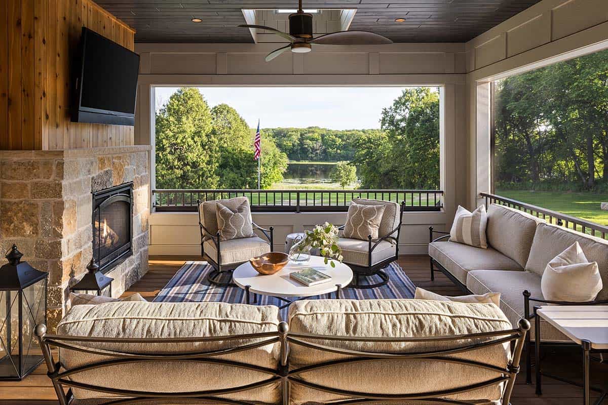Screened porch with stone fireplace, wicker furniture, and lake view