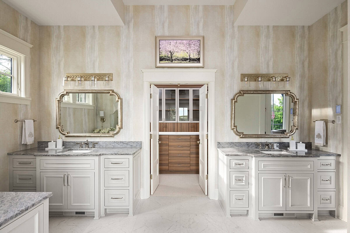Primary bathroom with double vanities, gray marble countertops, and ornate framed mirrors