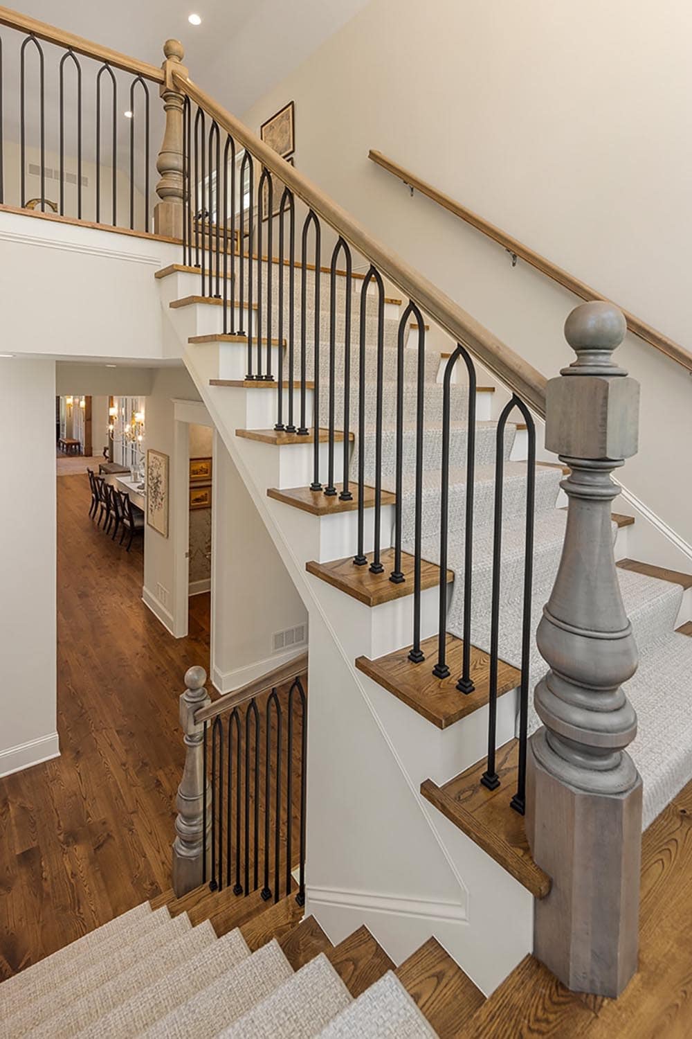 Curved staircase with wrought-iron arched balusters and wood newel posts