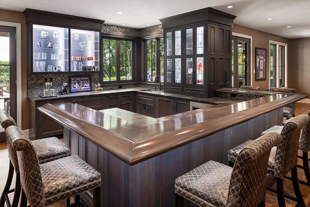 L-shaped wet bar with copper countertop and lighted glass display cabinets