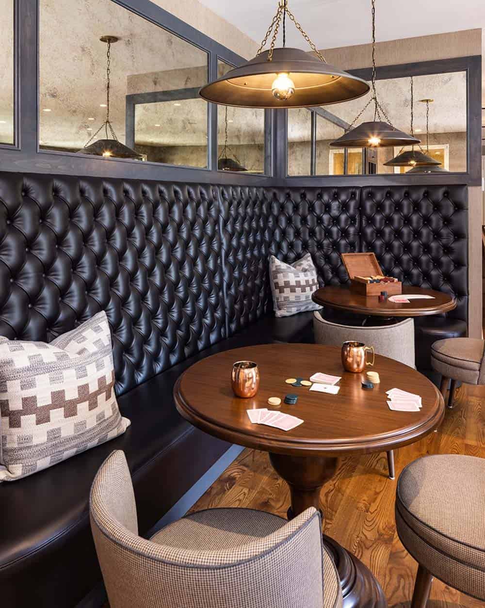 Game room nook with tufted leather banquette and round card tables