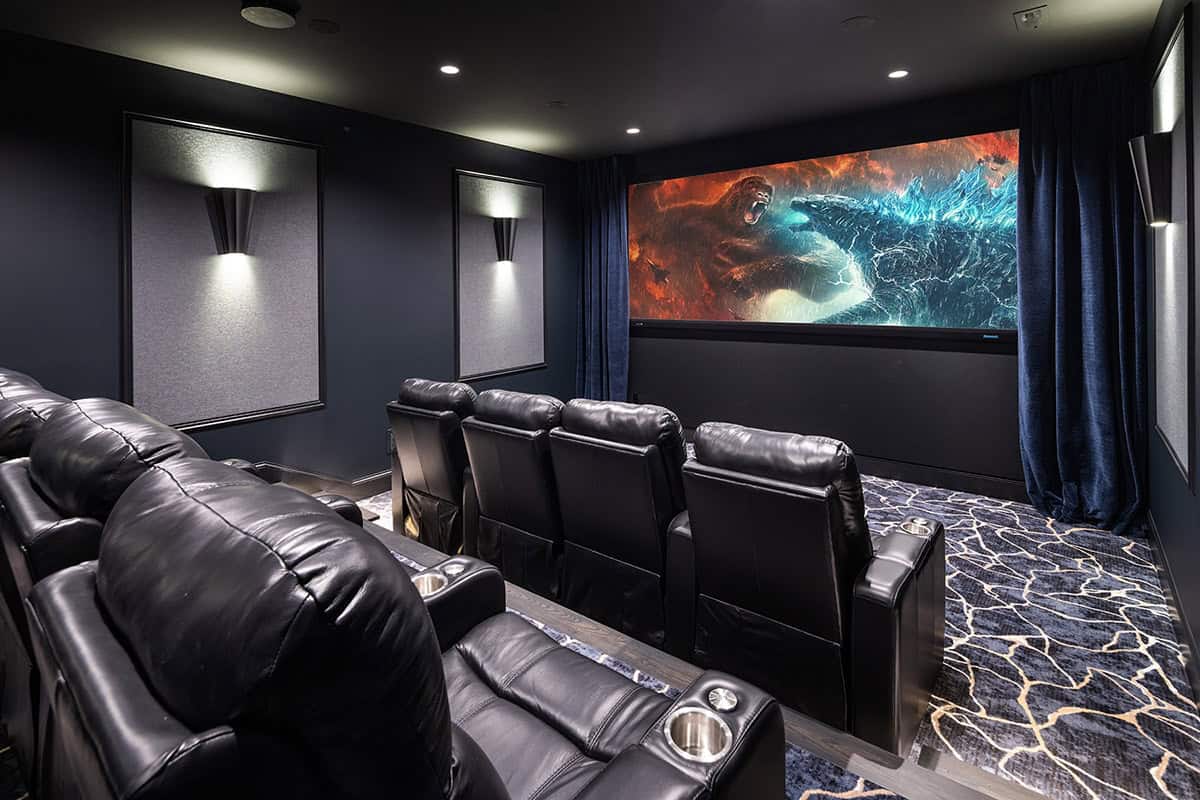 Home theater with black leather recliners and patterned carpet