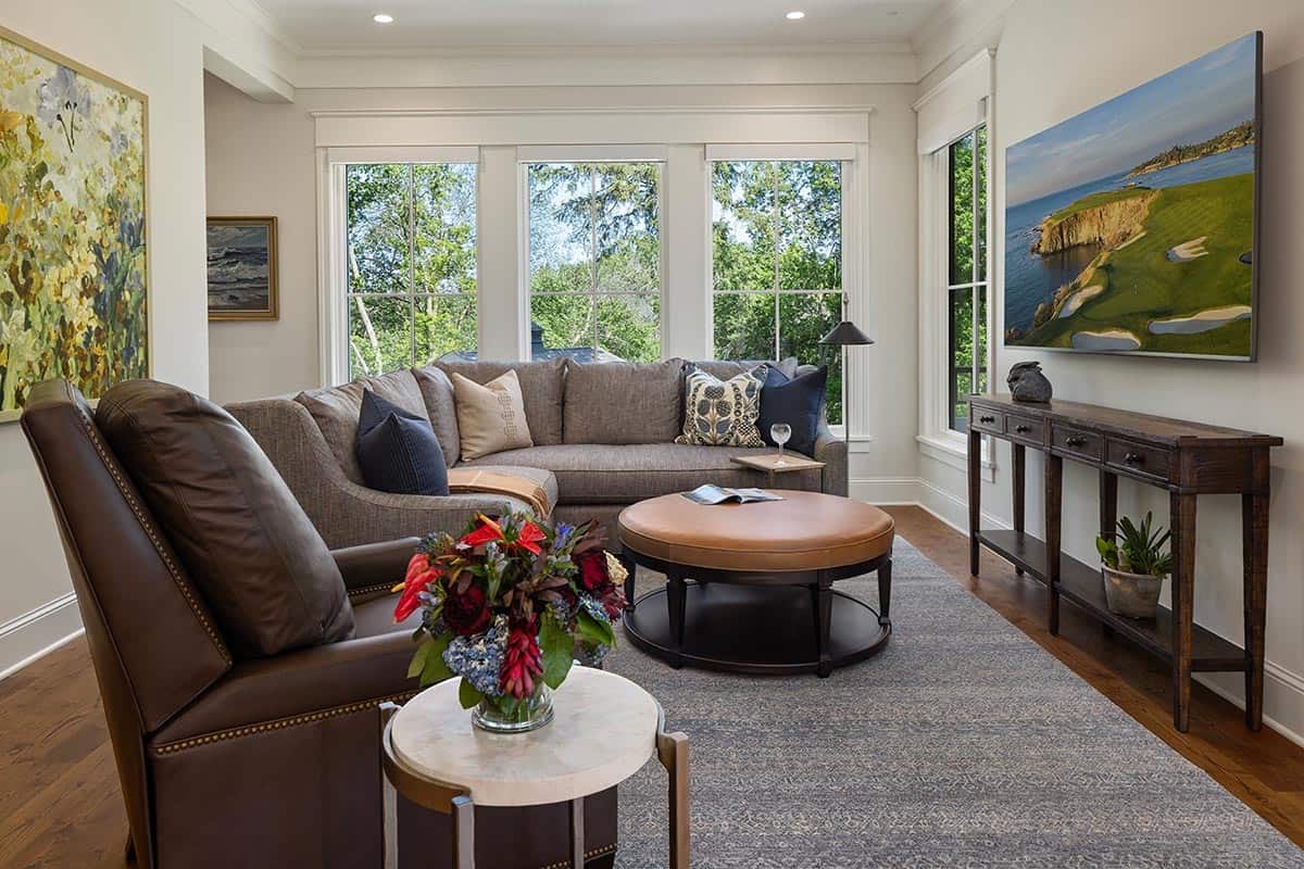 Sitting room with sectional sofa, leather armchair, and wooded window view