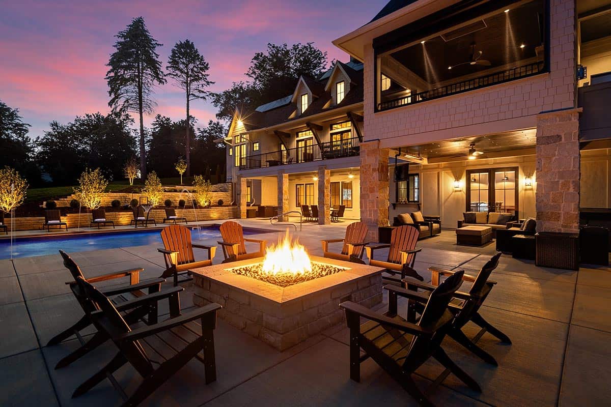 Twilight view of backyard pool, firepit with Adirondack chairs, and covered patio