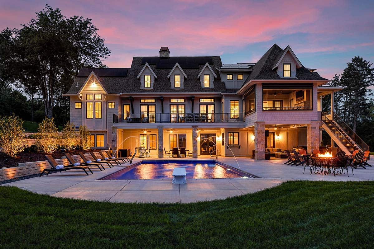 Rear exterior at dusk showing pool, multiple balconies, and stone columns