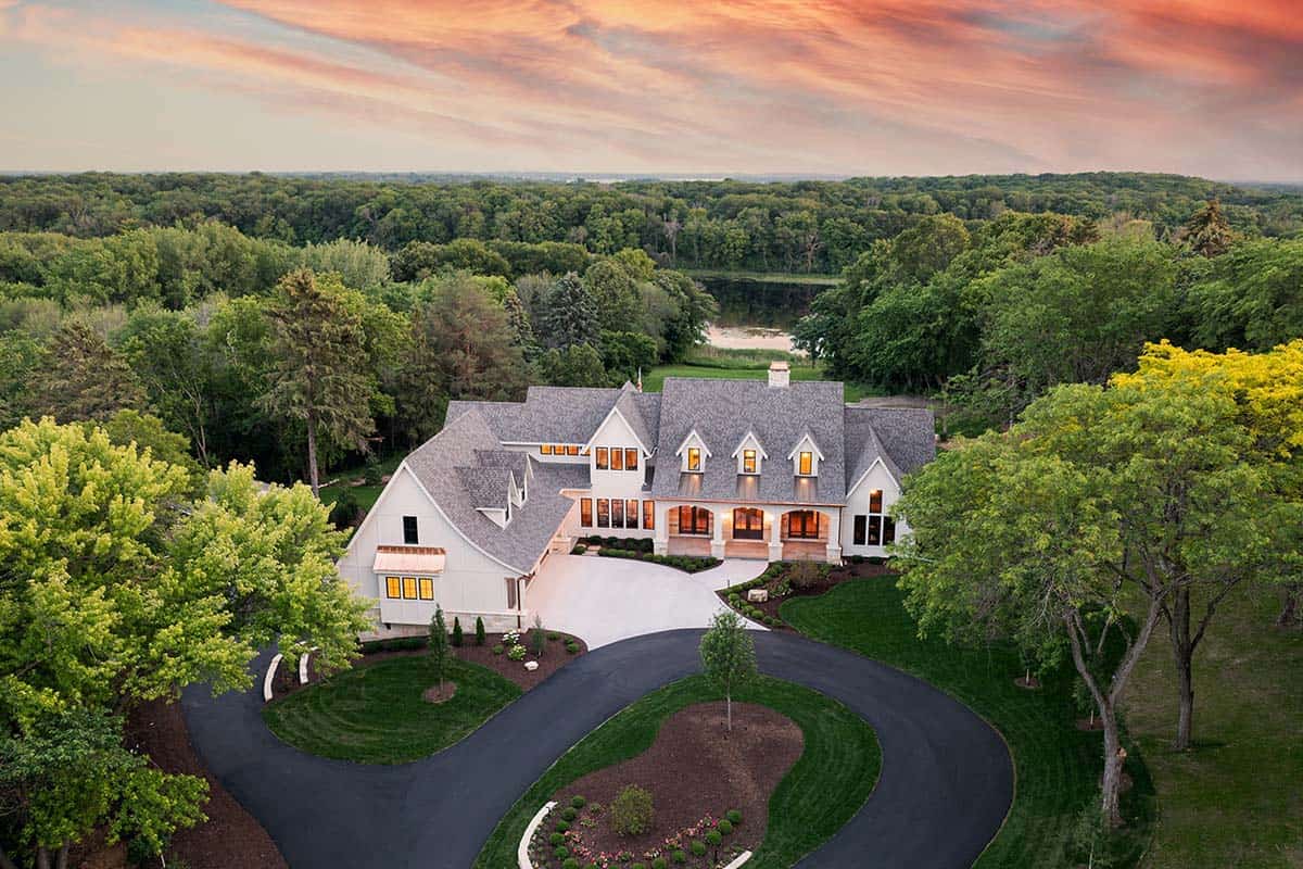 Aerial twilight view of estate showing roofline, circular drive, and lake beyond