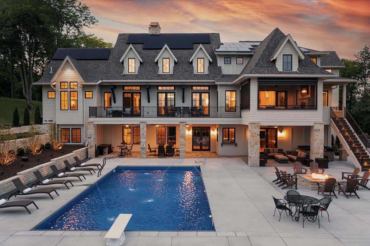 Rear exterior at dusk with pool, lounge chairs, firepit, and dual staircases