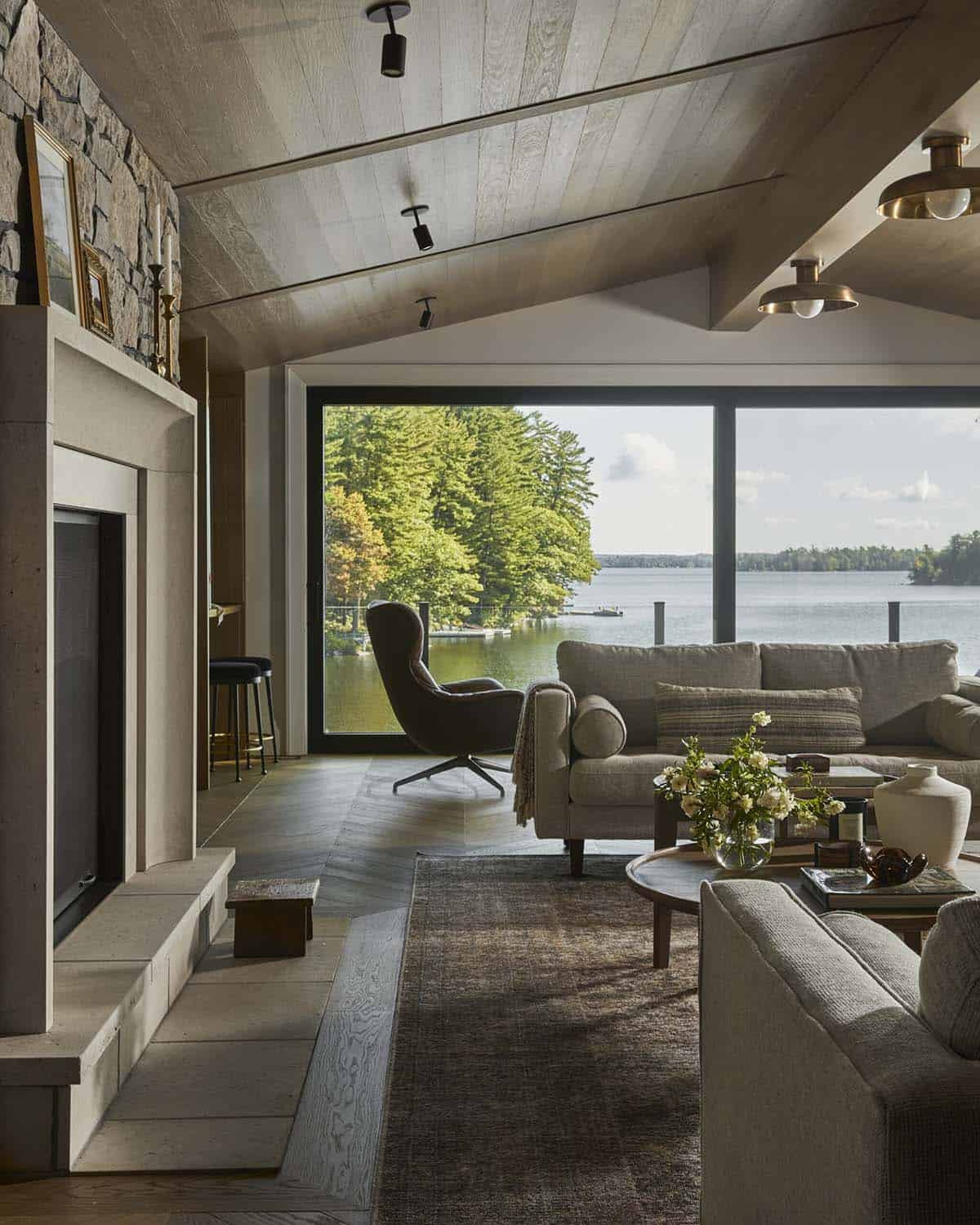 Living room seating area with lake view, cane-back chairs, and stone fireplace hearth