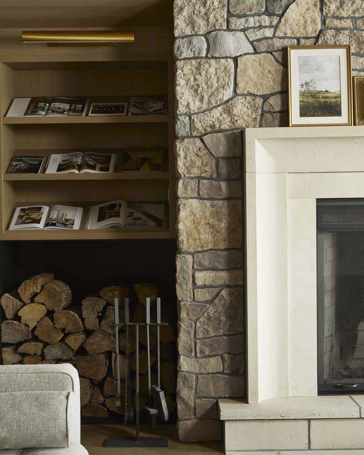 Close-up of fieldstone fireplace surround with limestone mantel and open bookshelf