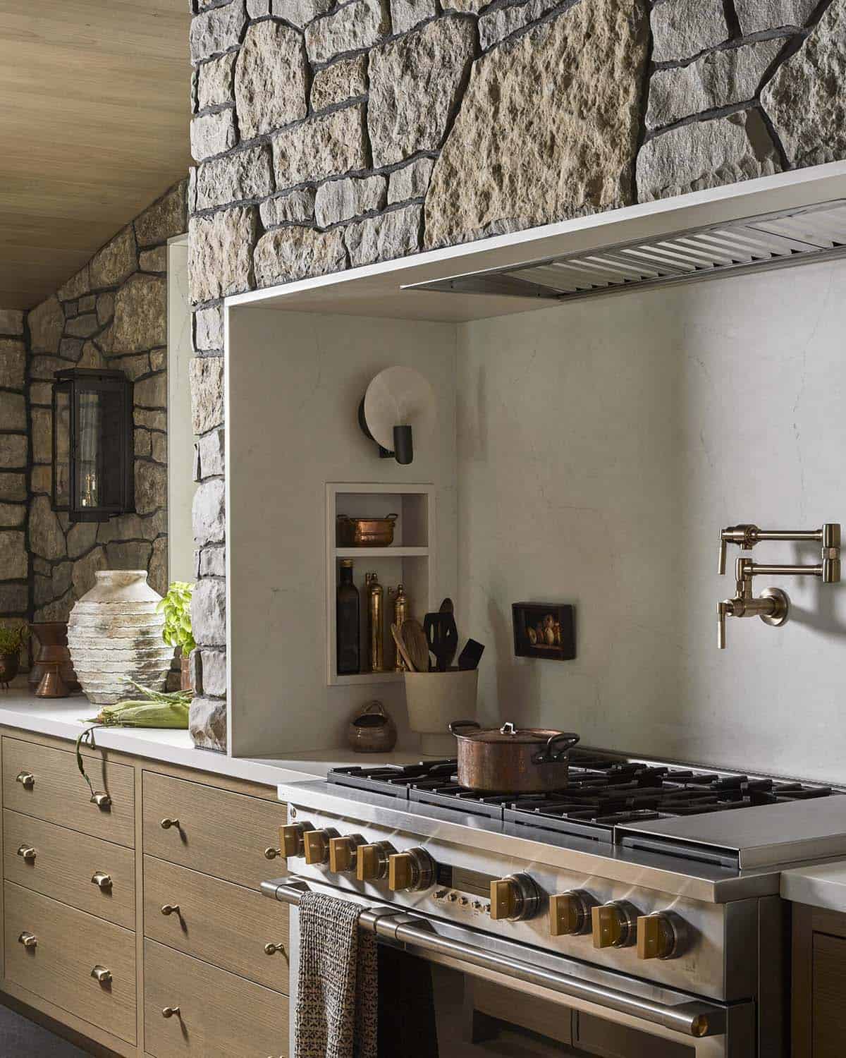 Kitchen range nook with stone hood surround and brass pot filler
