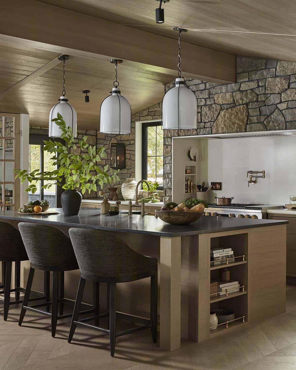 Kitchen island with white pendant lights, bar stools, and range beyond