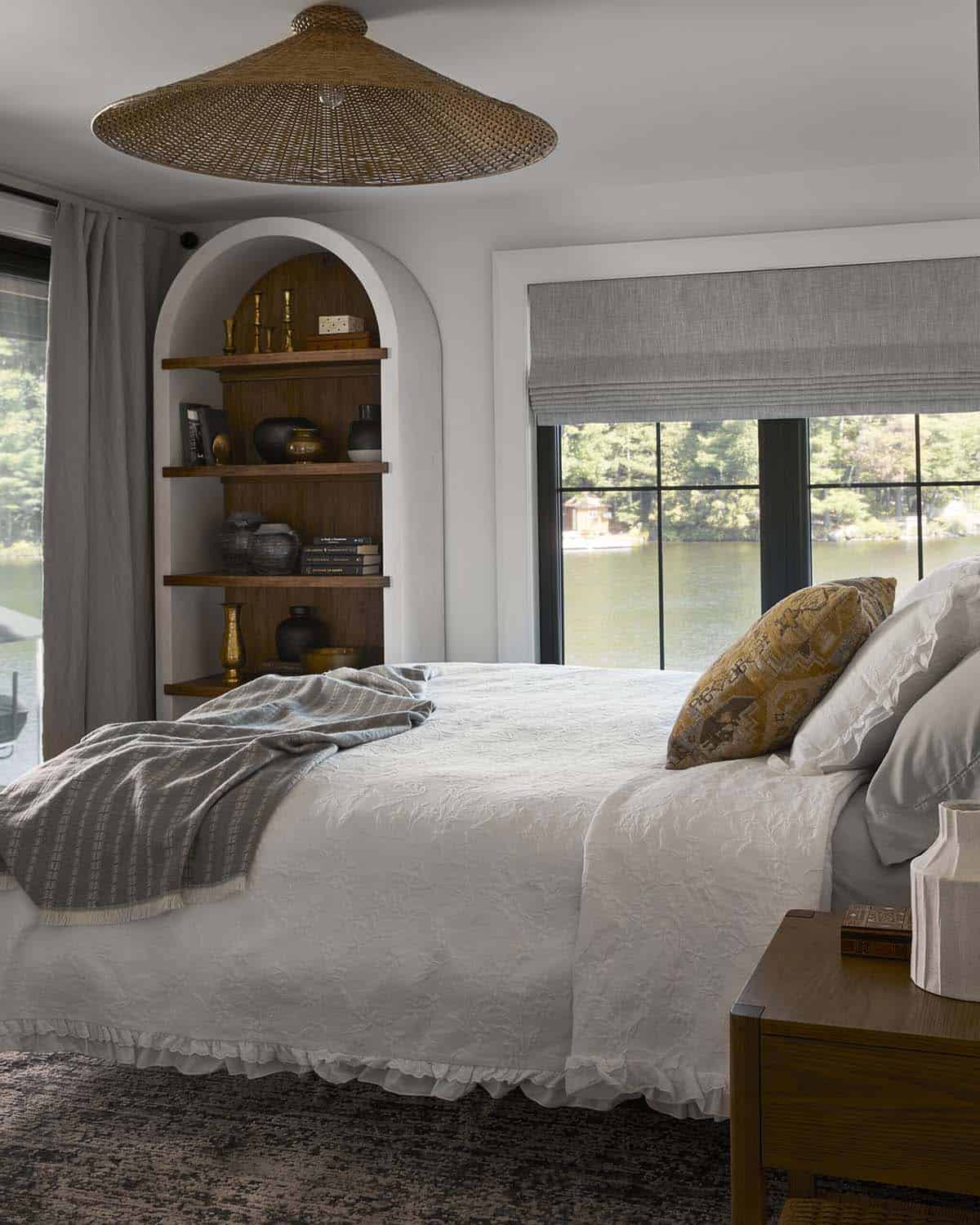 Bedroom with woven pendant light, arched shelving nook, and lake view window
