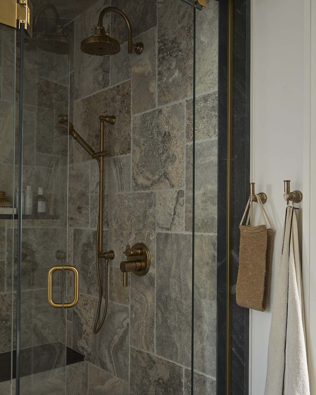 Walk-in shower with stone tile and brass rainfall fixtures