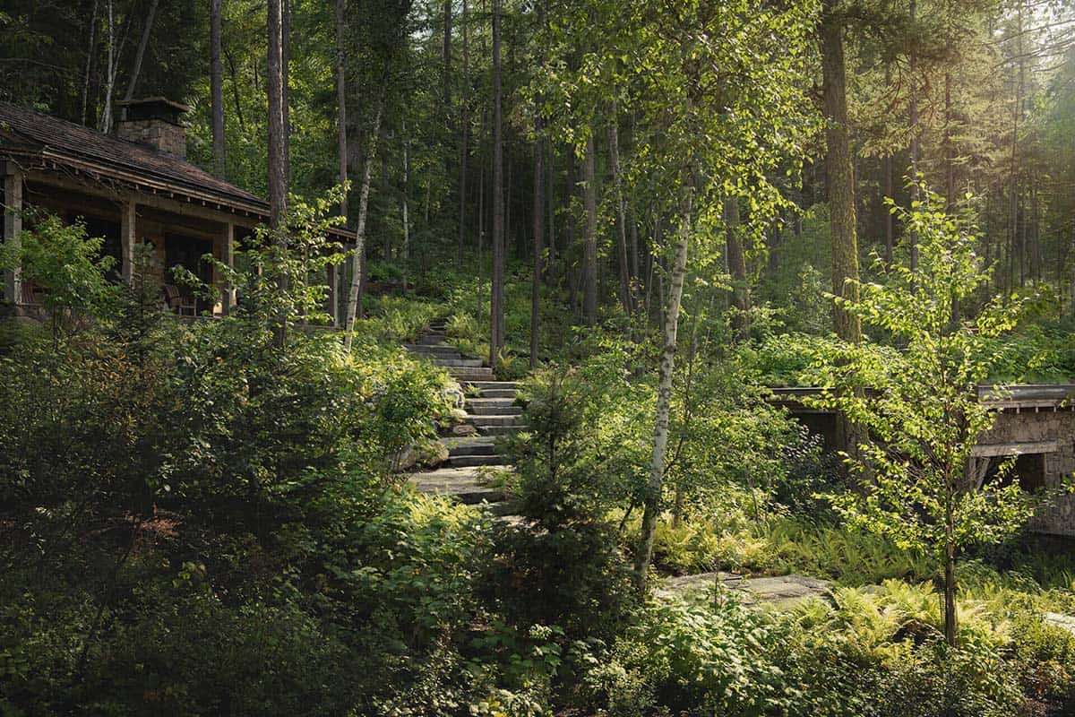 Stone steps winding through forest path to lakeside cabin