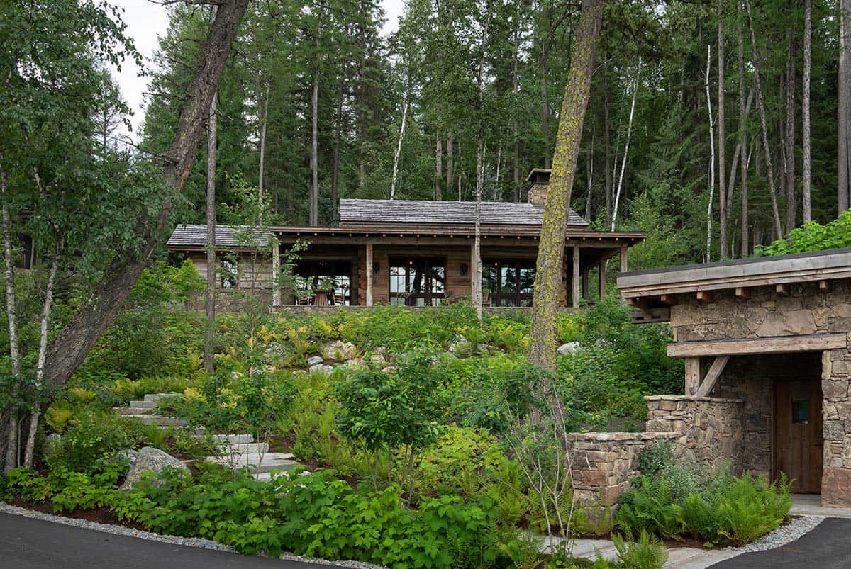 Rustic lakeside cabin with covered porch seen through forest