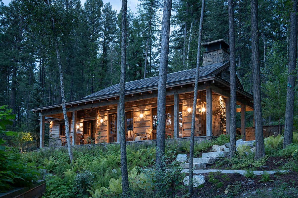 Log cabin exterior glowing at twilight among tall pines