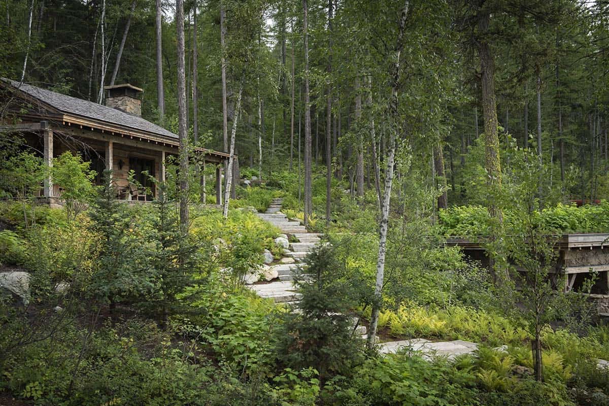 Rustic lakeside cabin with covered porch seen through forest