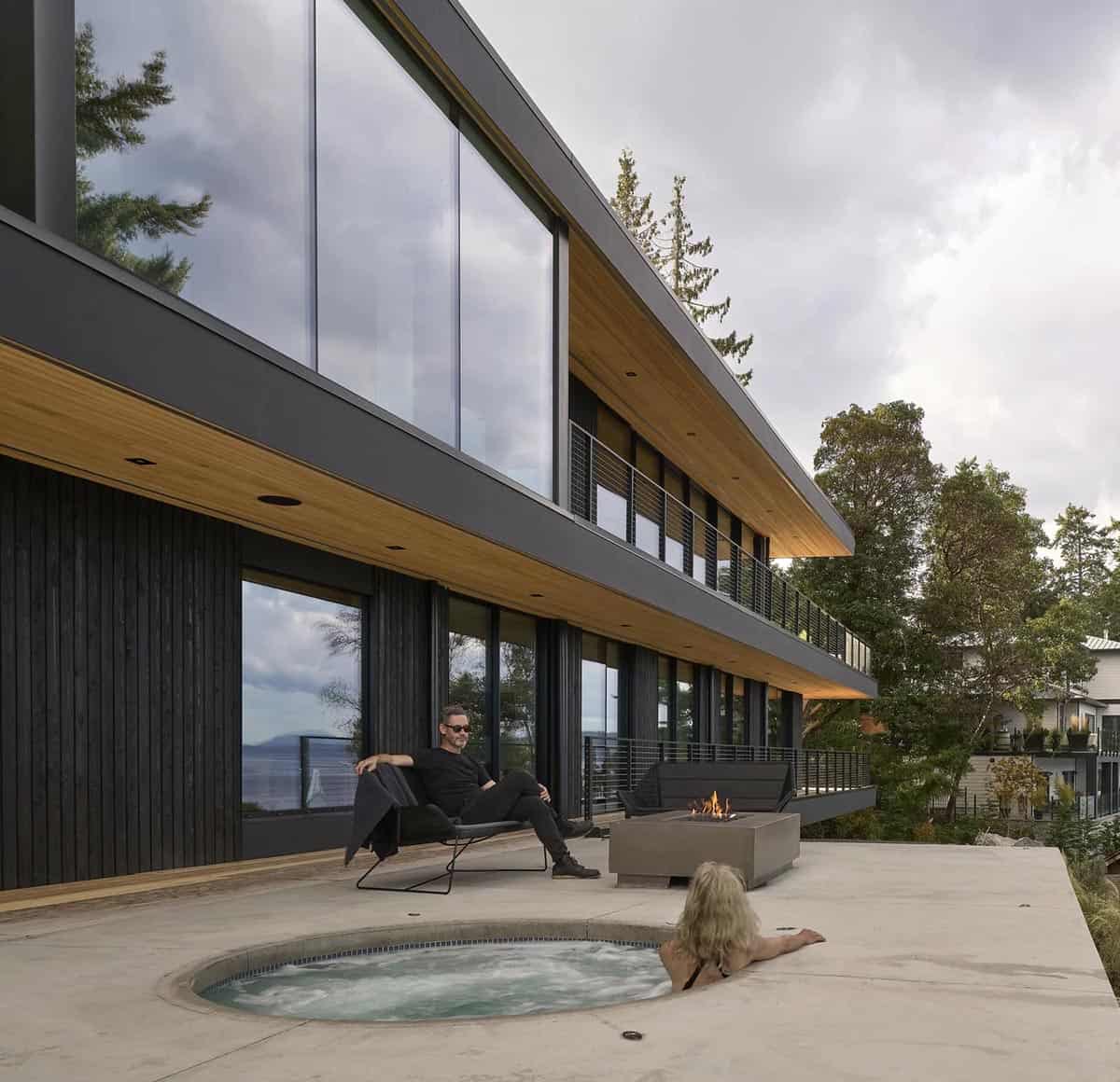 Homeowners relaxing by the hot tub and fire table on Layer House's lower terrace