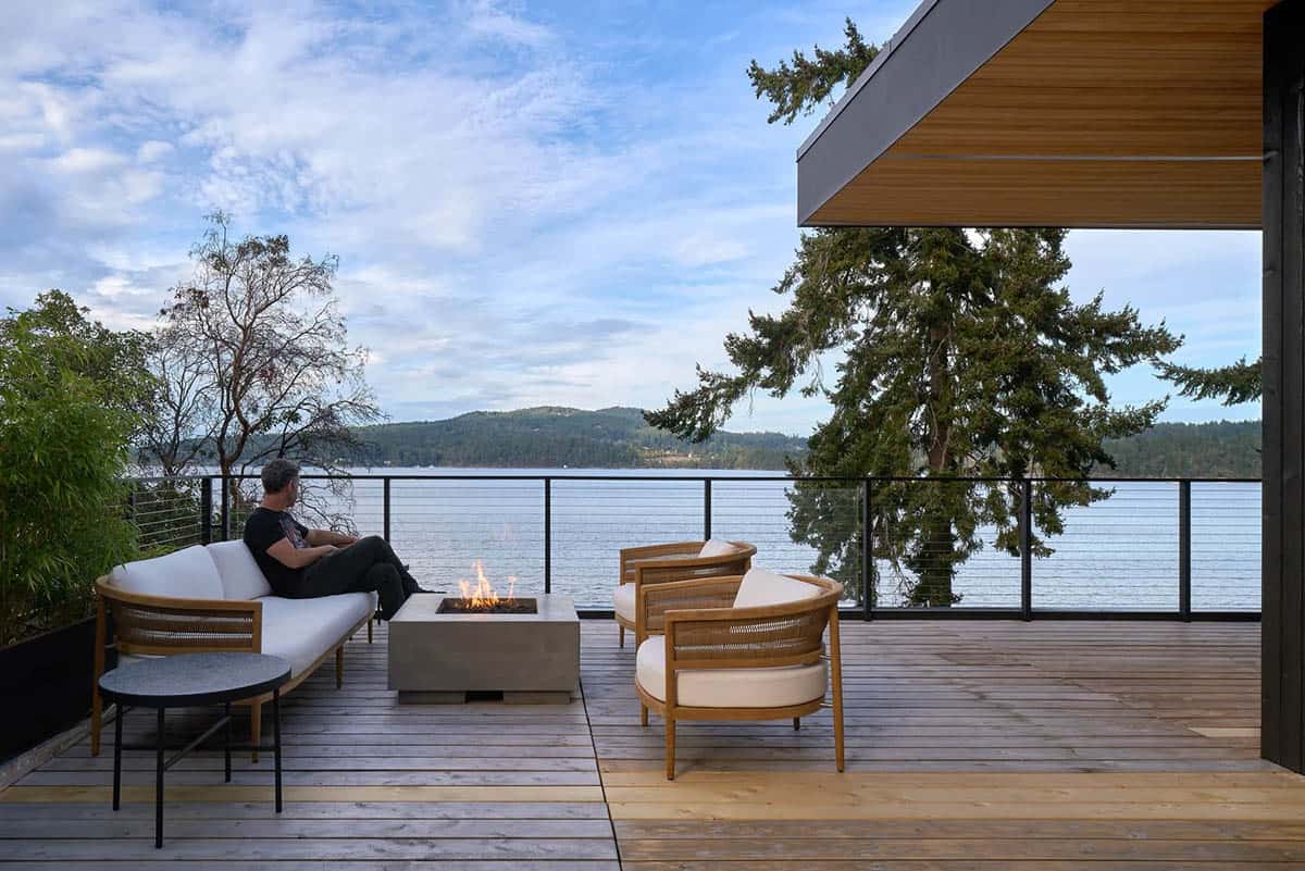 Outdoor lounge area on Layer House's deck with fire table overlooking the water