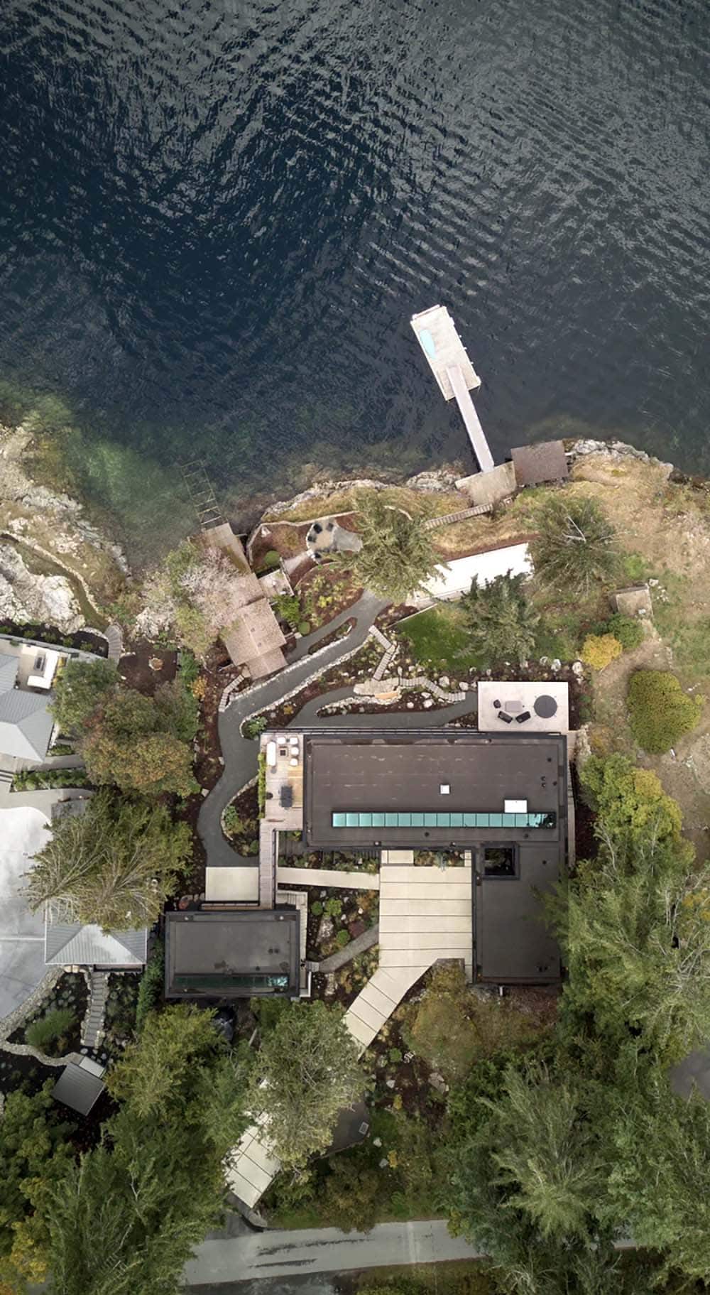  Aerial view of Layer House's waterfront site, dock, and layered roof forms