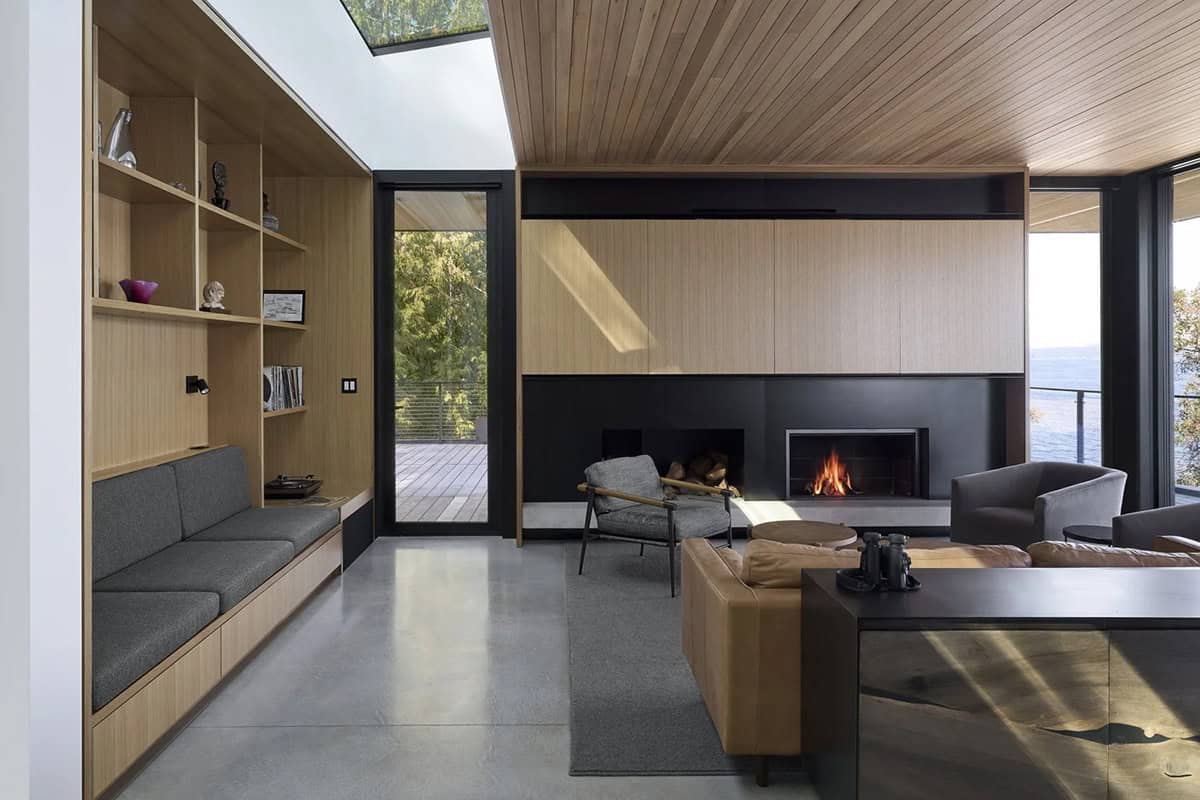 Living room nook in Layer House with built-in shelving, fireplace, and forest views