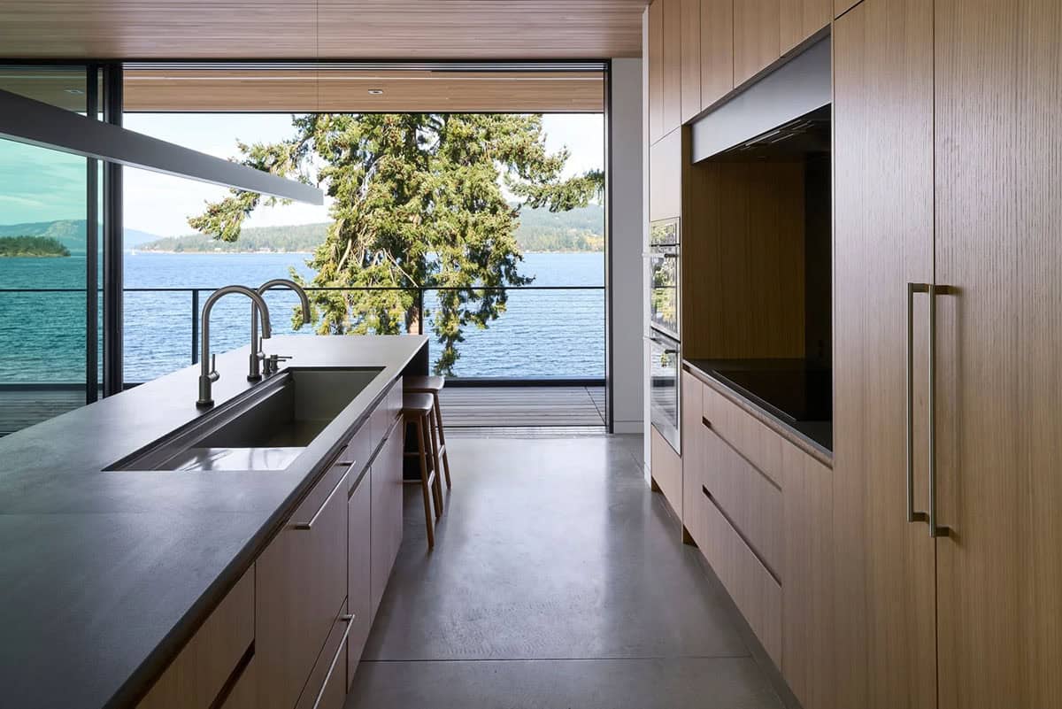 Kitchen counter in Layer House framing a tree and the waters of Saanich Inlet