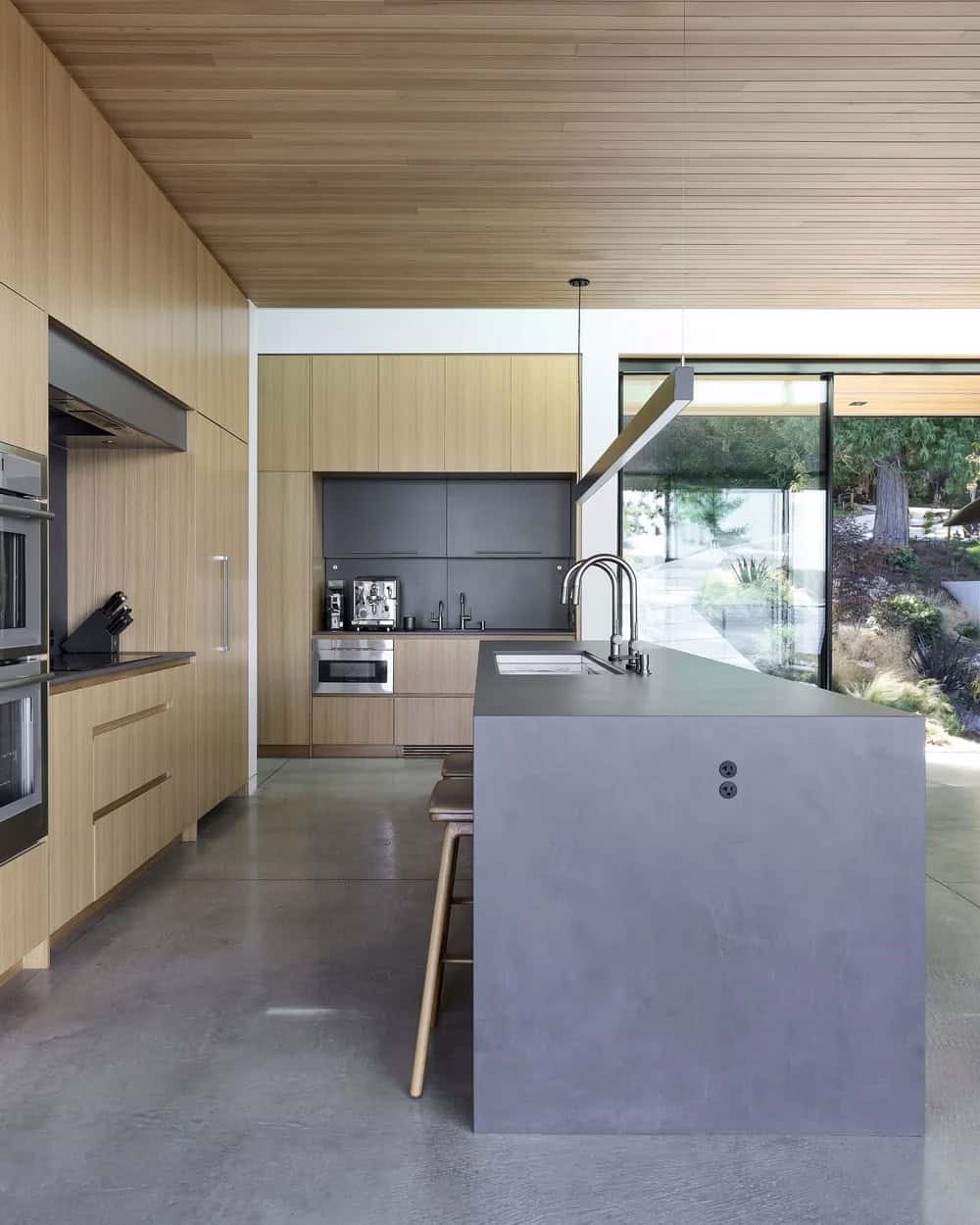 Kitchen island with concrete waterfall countertop in Layer House's secondary kitchen