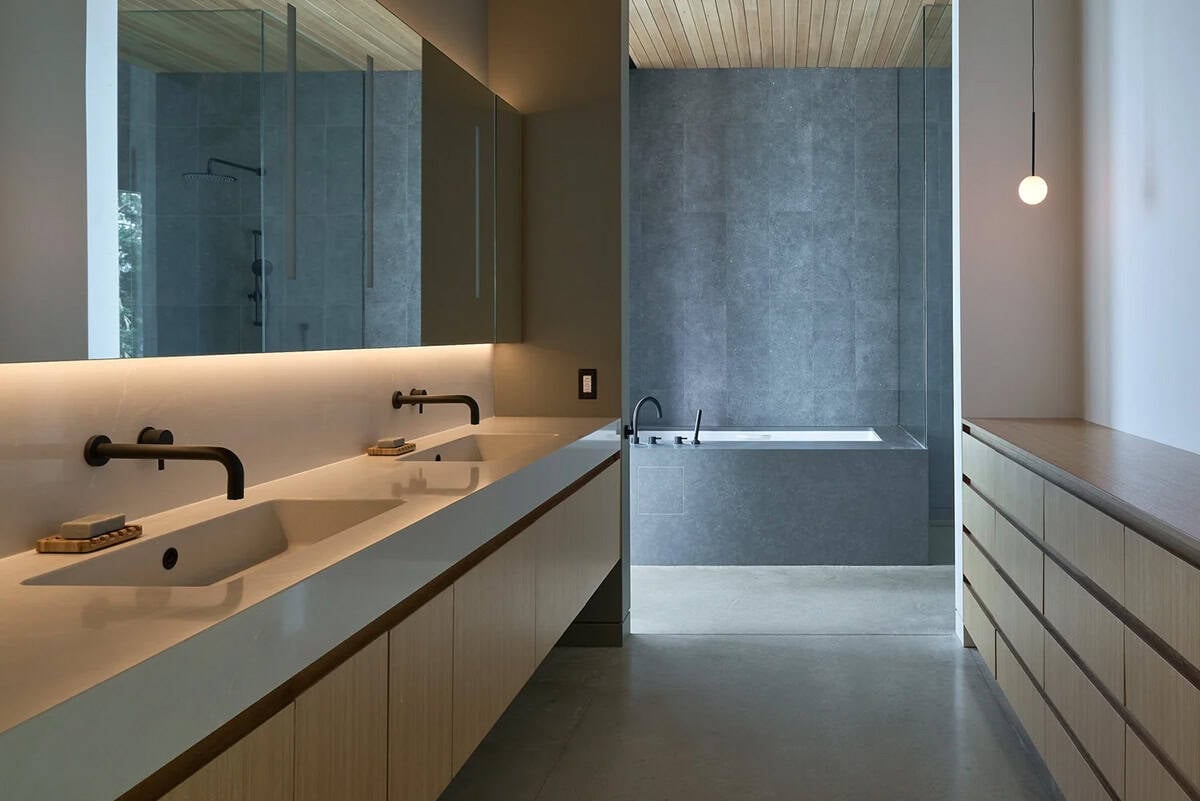 Primary bathroom in Layer House with soaking tub, dark tile, and oak cabinetry