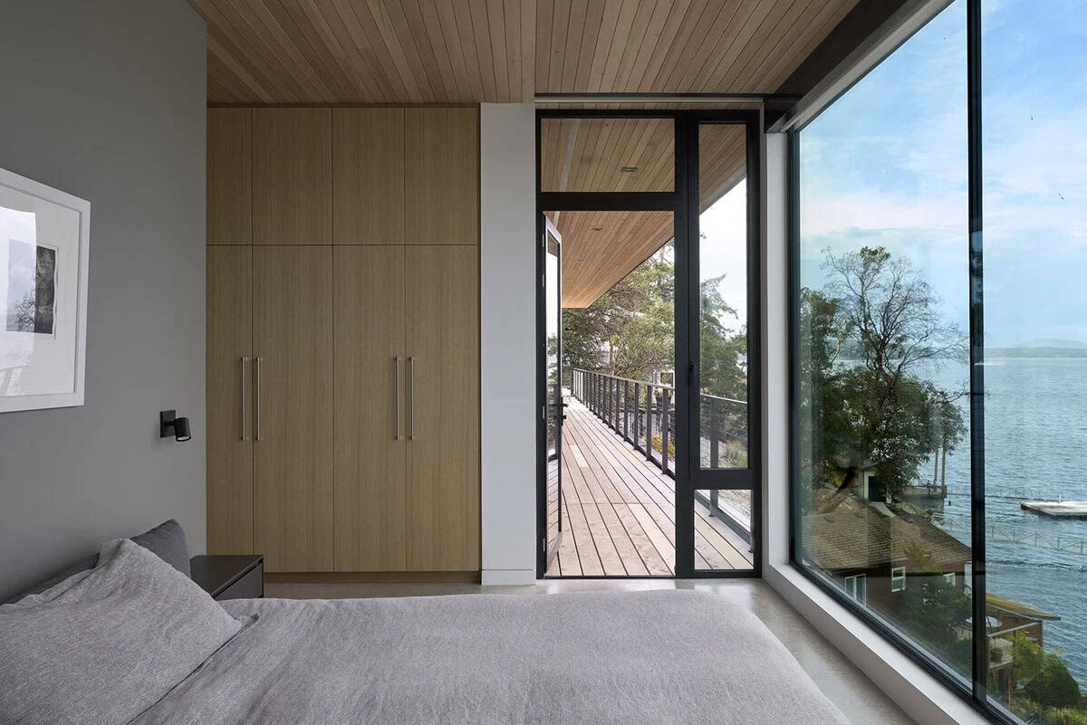 Primary bedroom in Layer House with built-in wardrobe and deck access overlooking the water