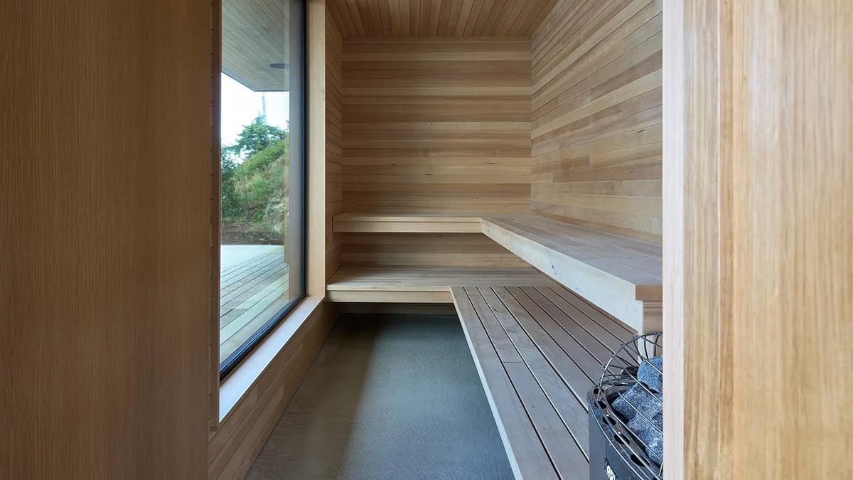 Cedar-lined sauna bench in Layer House's accessory building, framing a forest view