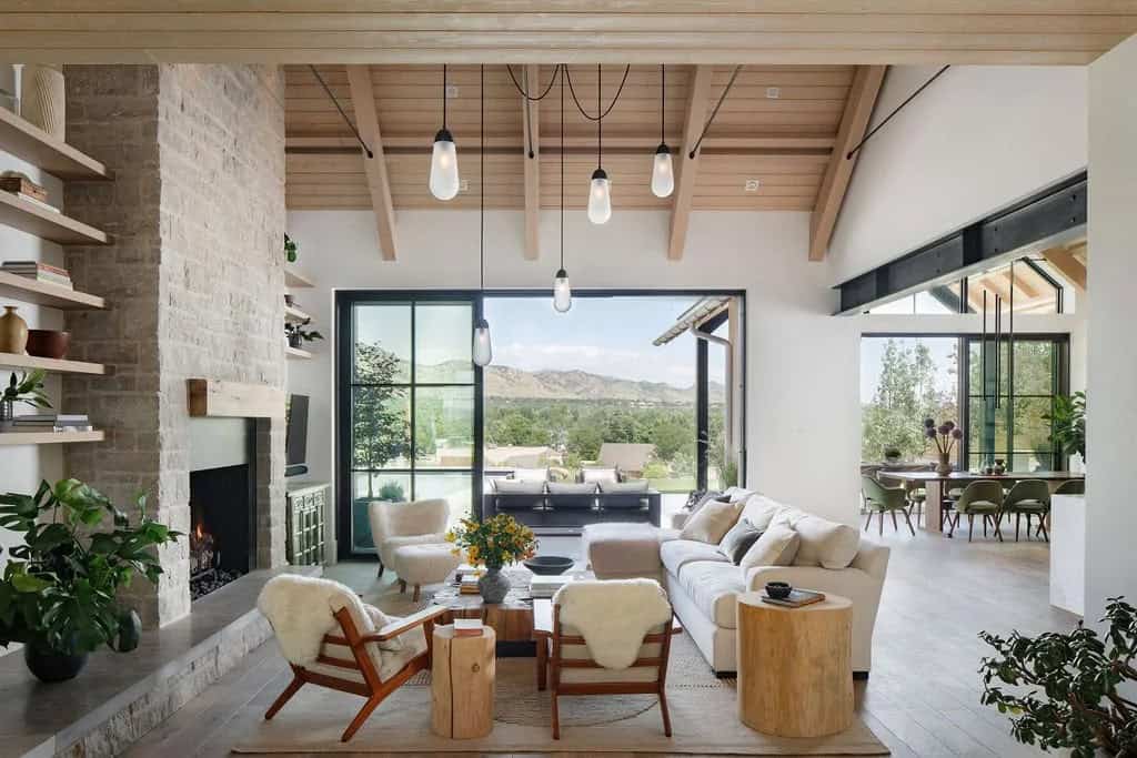 Wide view of living and dining space with vaulted wood ceiling, steel beam, and floor-to-ceiling windows