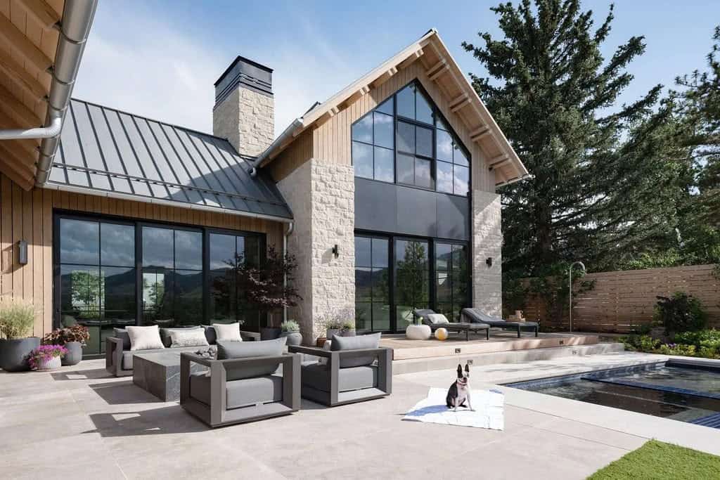 Backyard patio and pool area with stone and wood gable facade, dog resting on a blanket
