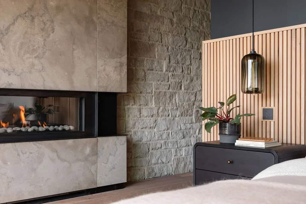 Close-up of linear fireplace flames beside stacked stone wall and slatted wood nightstand divider