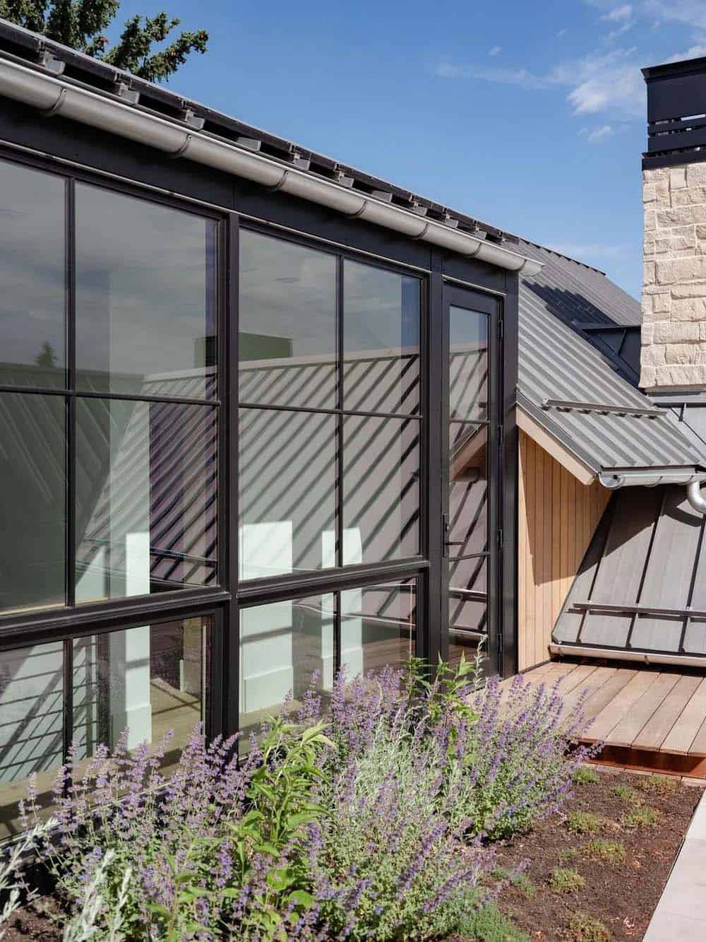 Exterior view of black-framed glass walls and standing-seam metal roof over a rooftop deck