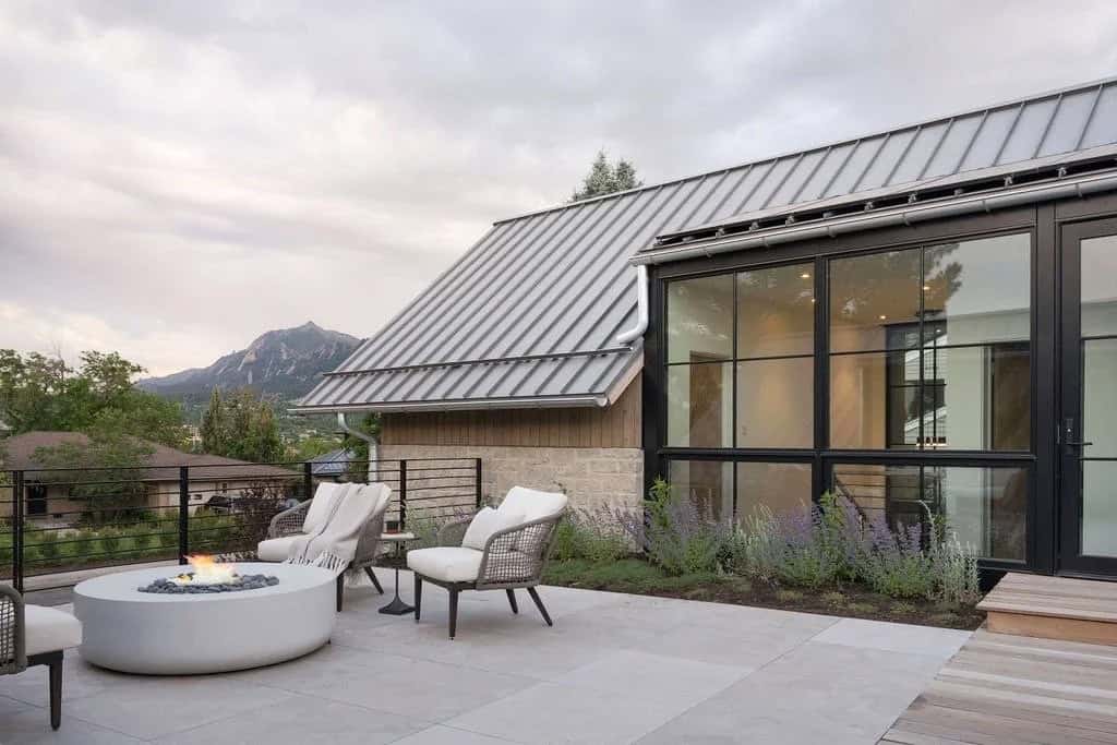 Rooftop patio with fire pit, woven lounge chairs, metal roof, and Flatirons mountain view