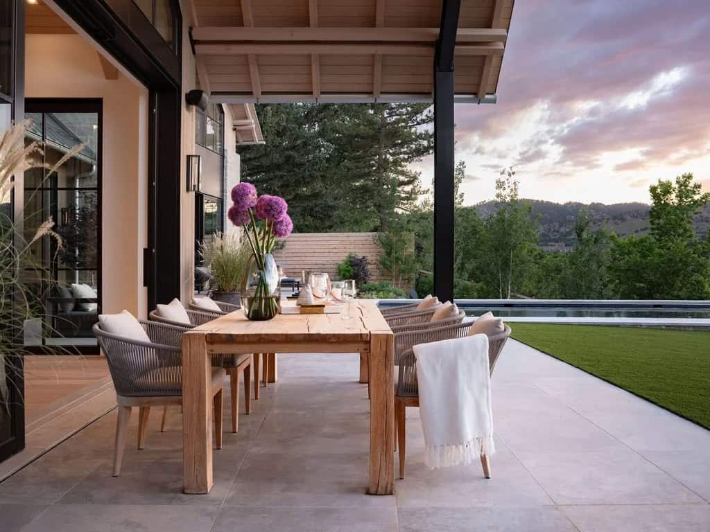 Outdoor dining table set for sunset with allium centerpiece on a covered patio overlooking hills