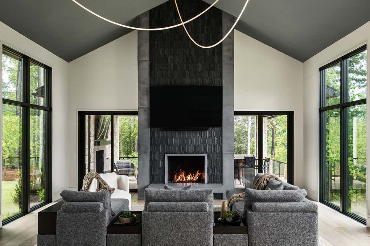 Vaulted living room with dark tiled fireplace, gray sectional, and wraparound windows