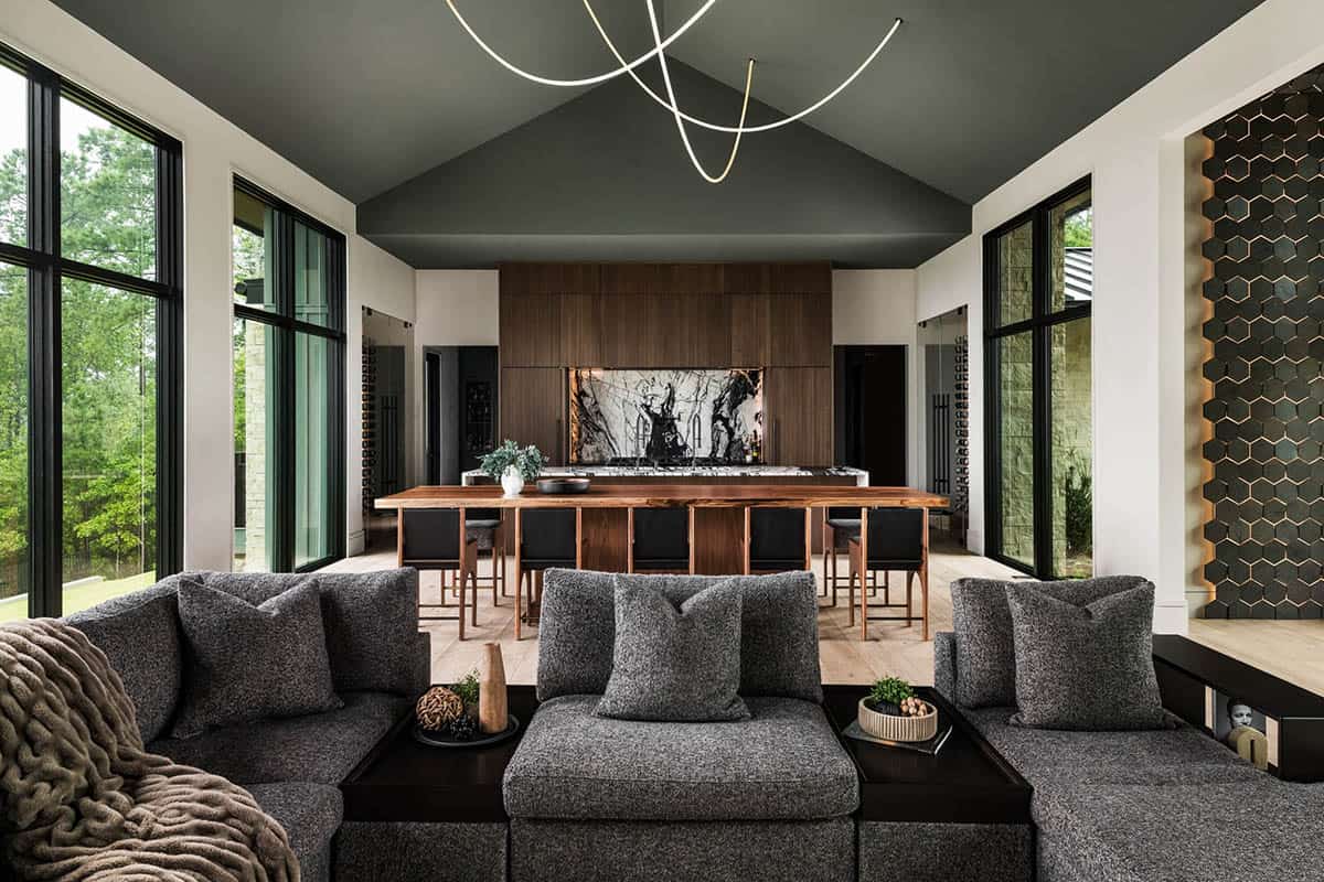 Open-concept living room facing wood-paneled kitchen with marble island