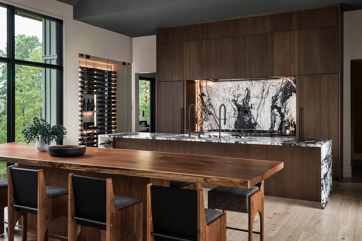 Kitchen with live-edge wood island, black bar stools, and marble waterfall backsplash
