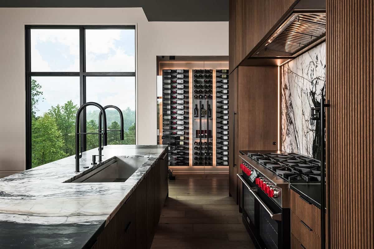 Kitchen island with black faucet, marble counters, and built-in glass wine wall