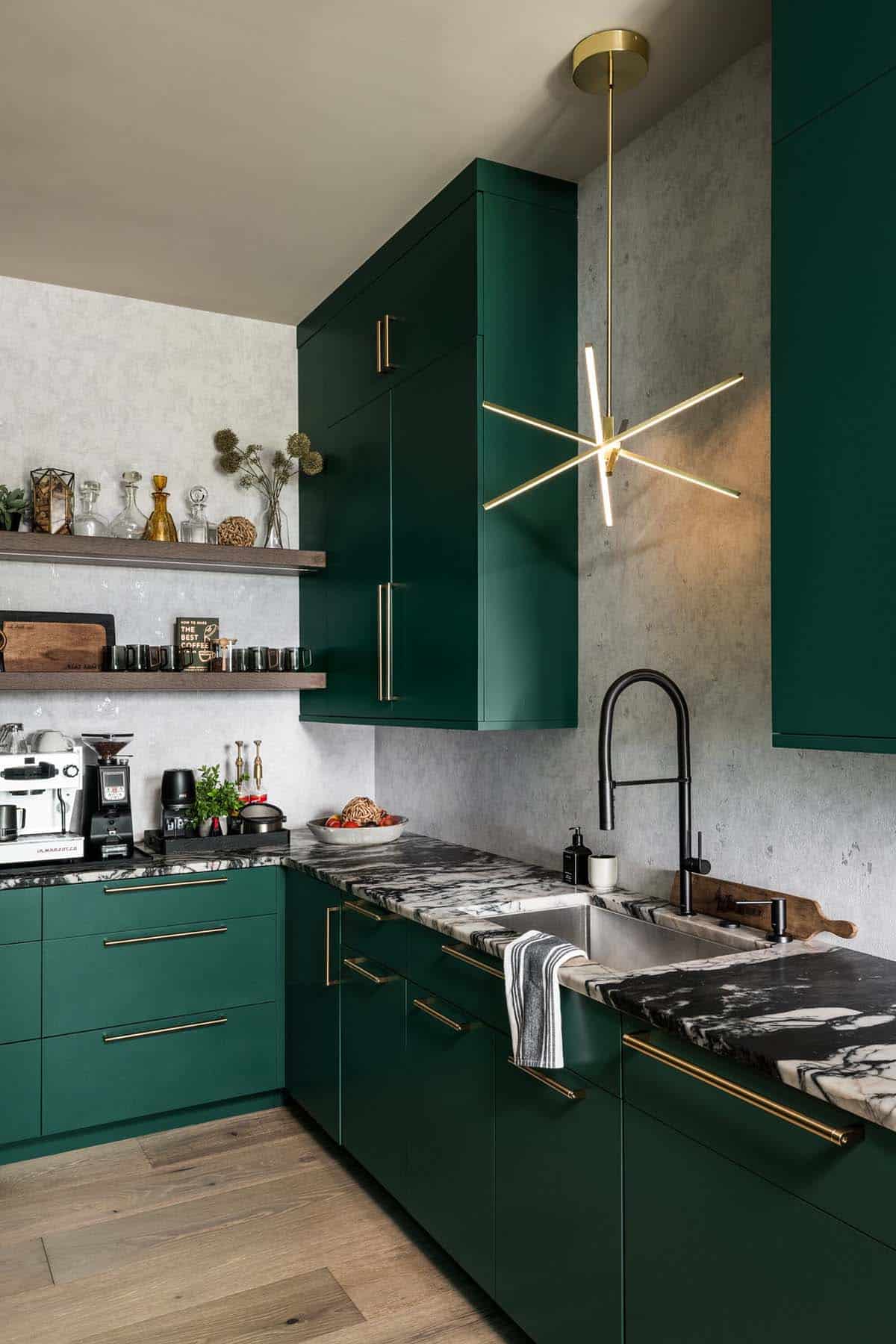 Emerald green kitchen cabinetry with brass hardware and marble countertop