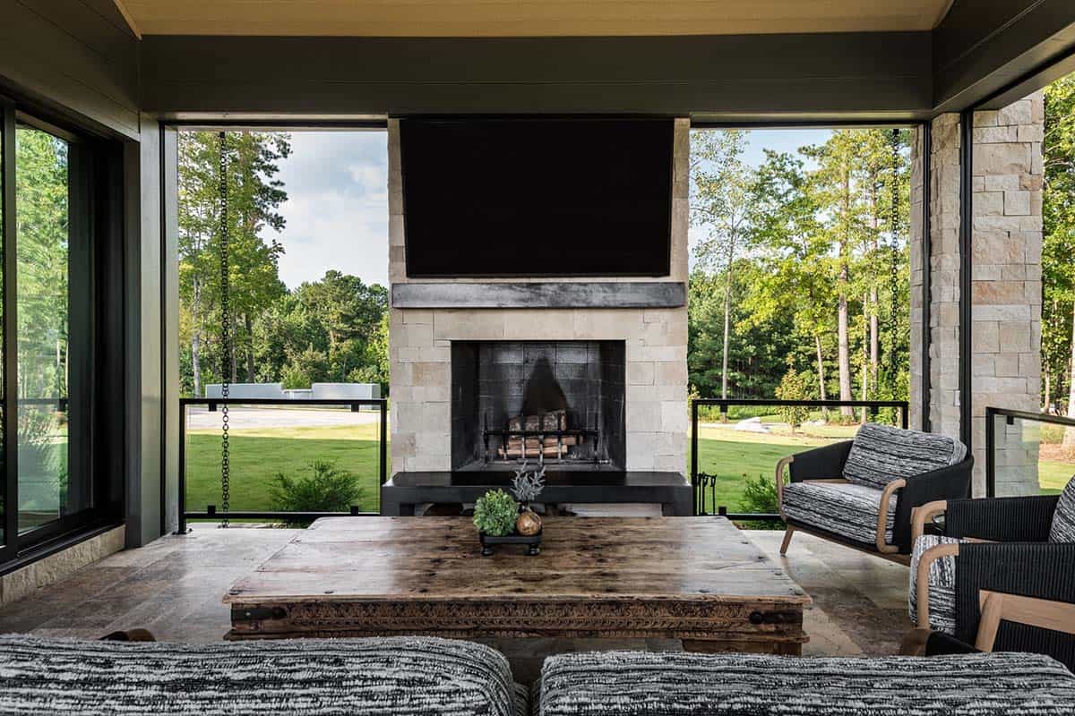 Screened porch with stone fireplace, mounted TV, and wooden coffee table