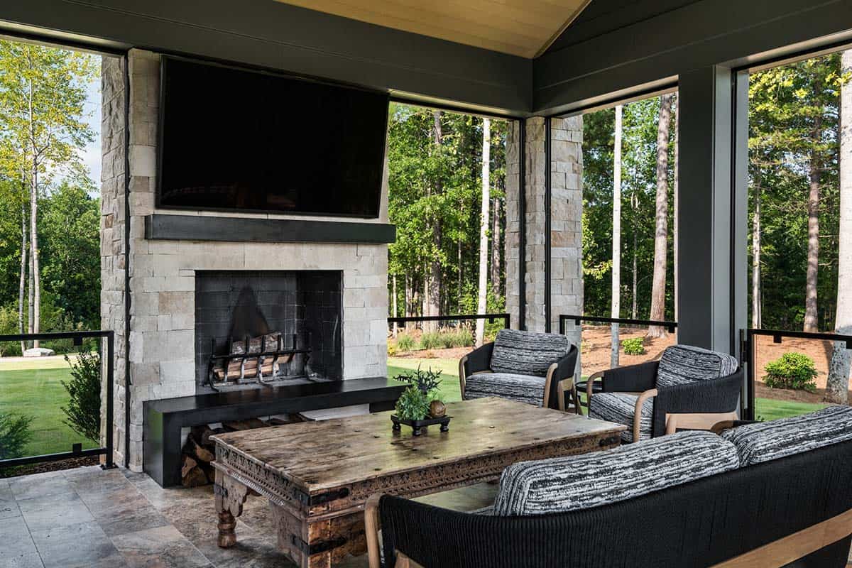 Covered outdoor living area with stone fireplace and woven lounge chairs