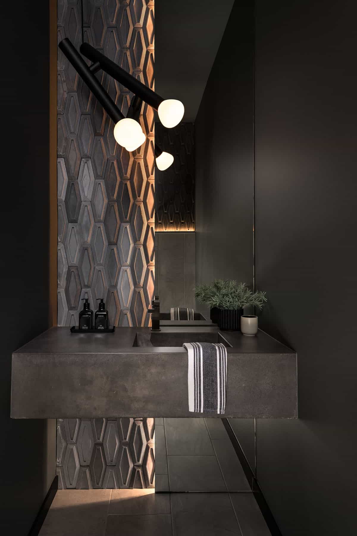 Dark powder room with floating concrete sink and geometric tile accent wall