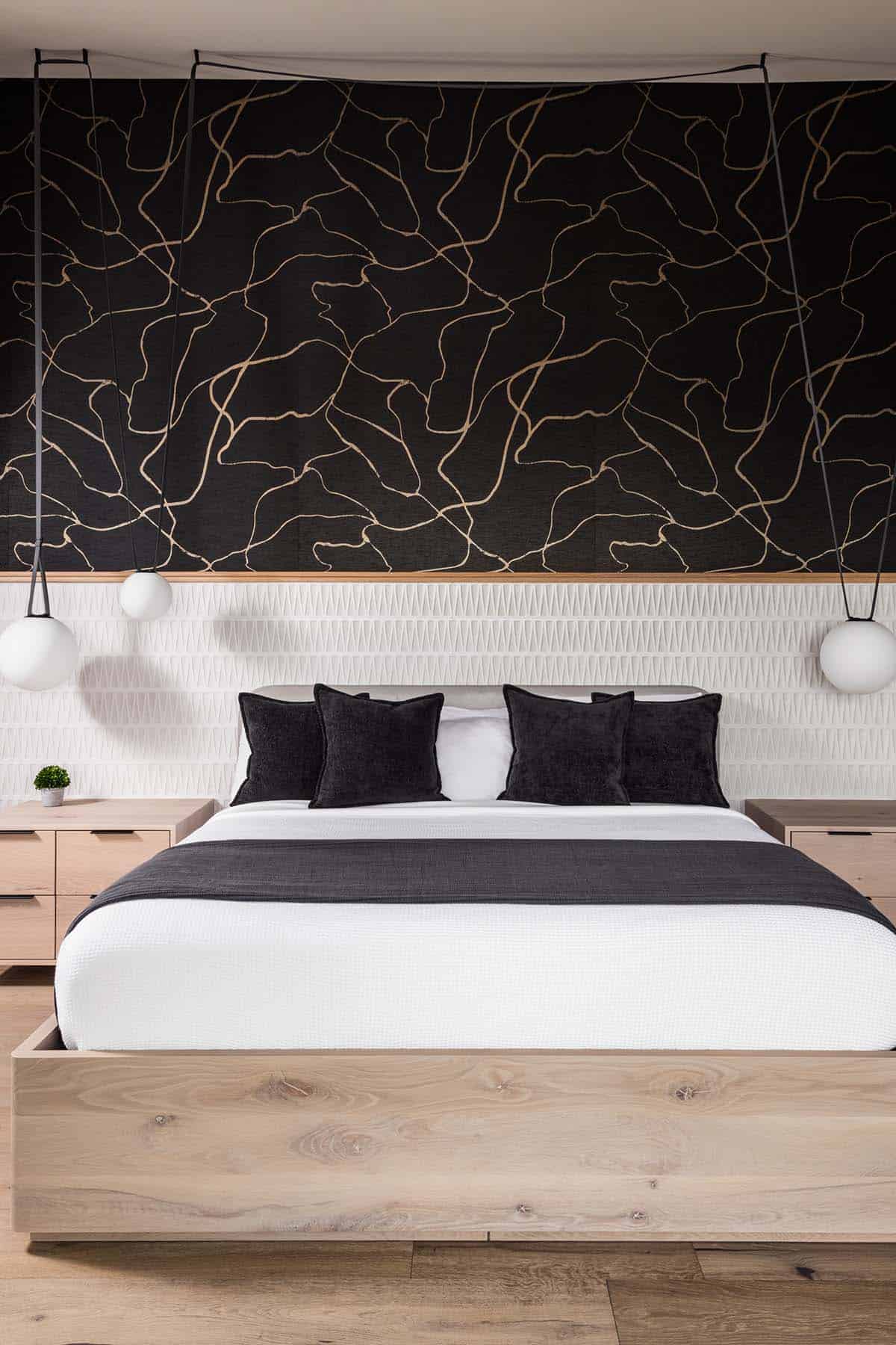 Bedroom with black-and-gold abstract wallpaper and light wood platform bed