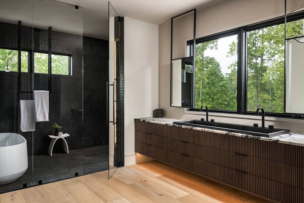 Primary bathroom with ribbed wood vanity, dual sinks, and glass shower enclosure